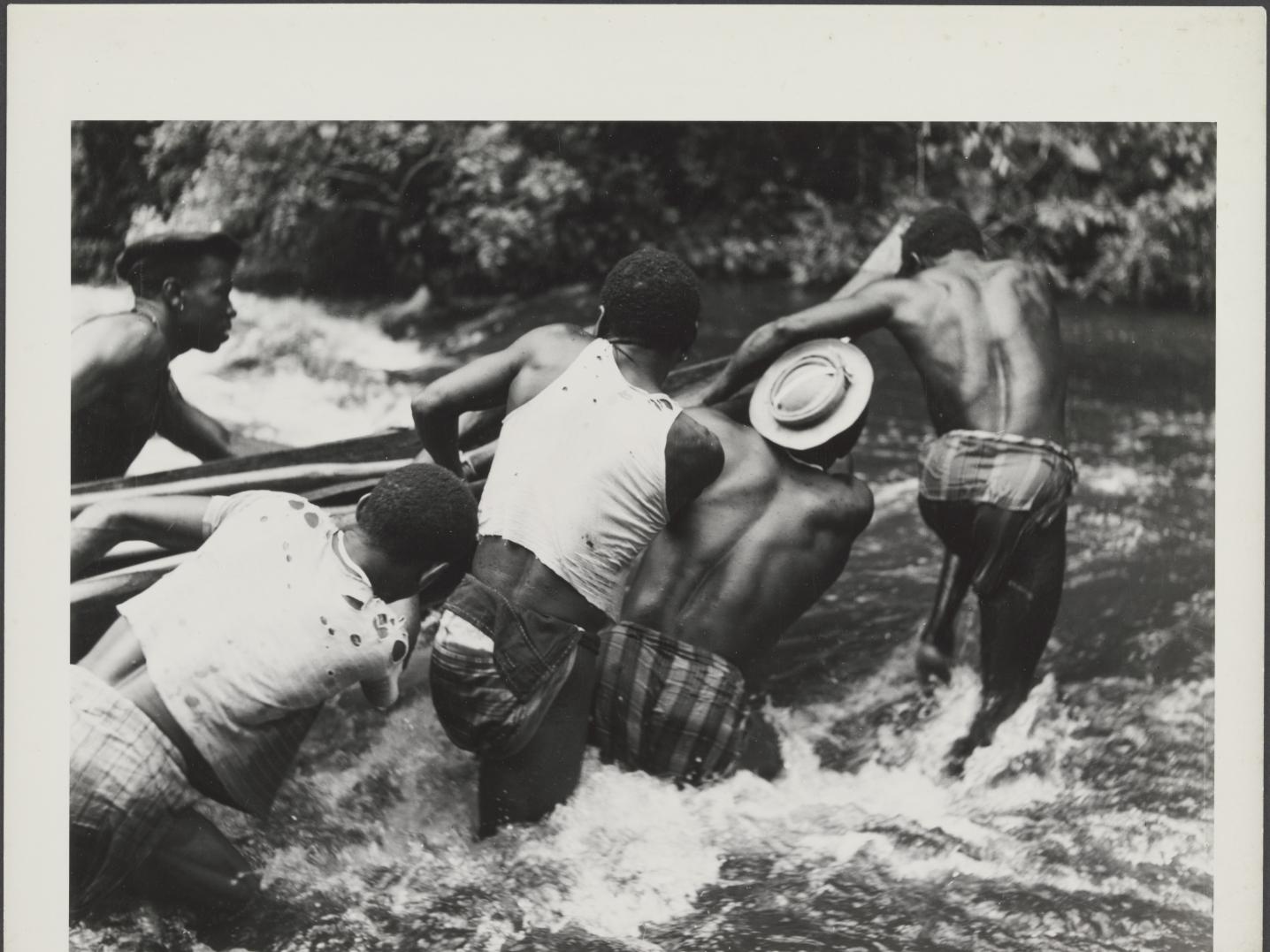 A group of surinamese Maroon men pulling a boat acroos a wild river