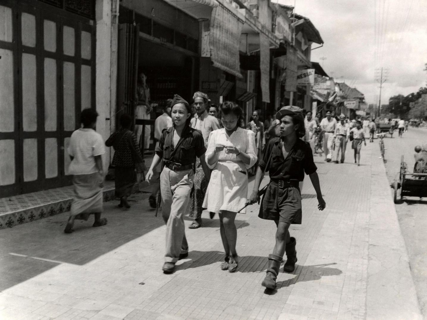 Three young Indonesians on the street, members of the armed youth organization KRIS.