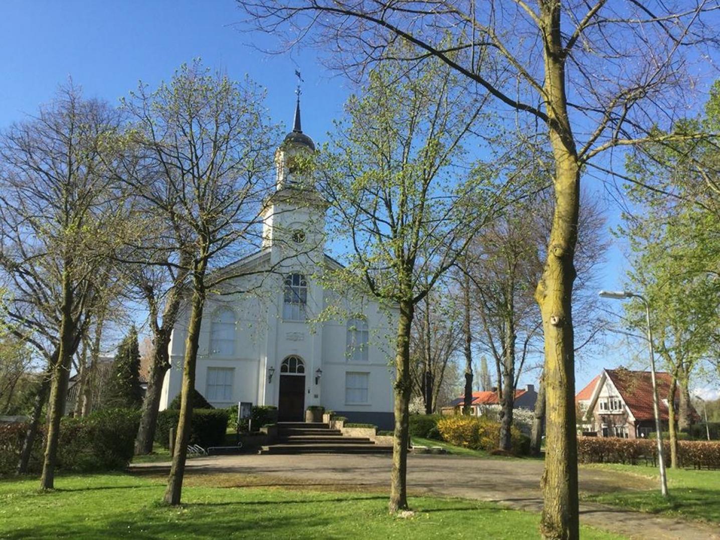 An old white building with large tower in the middle, a lawn and trees suurounding it, serving as the Van 't  Lindenhoutmuseum in Nijmegen
