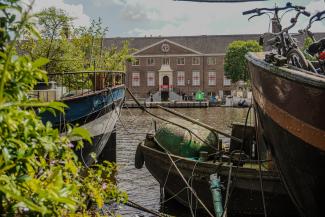 view of the Nieuwe Herengracht building from across the canal, in between two canal boats